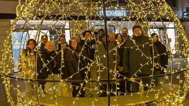 Students standing behind circular structure with twinkle light